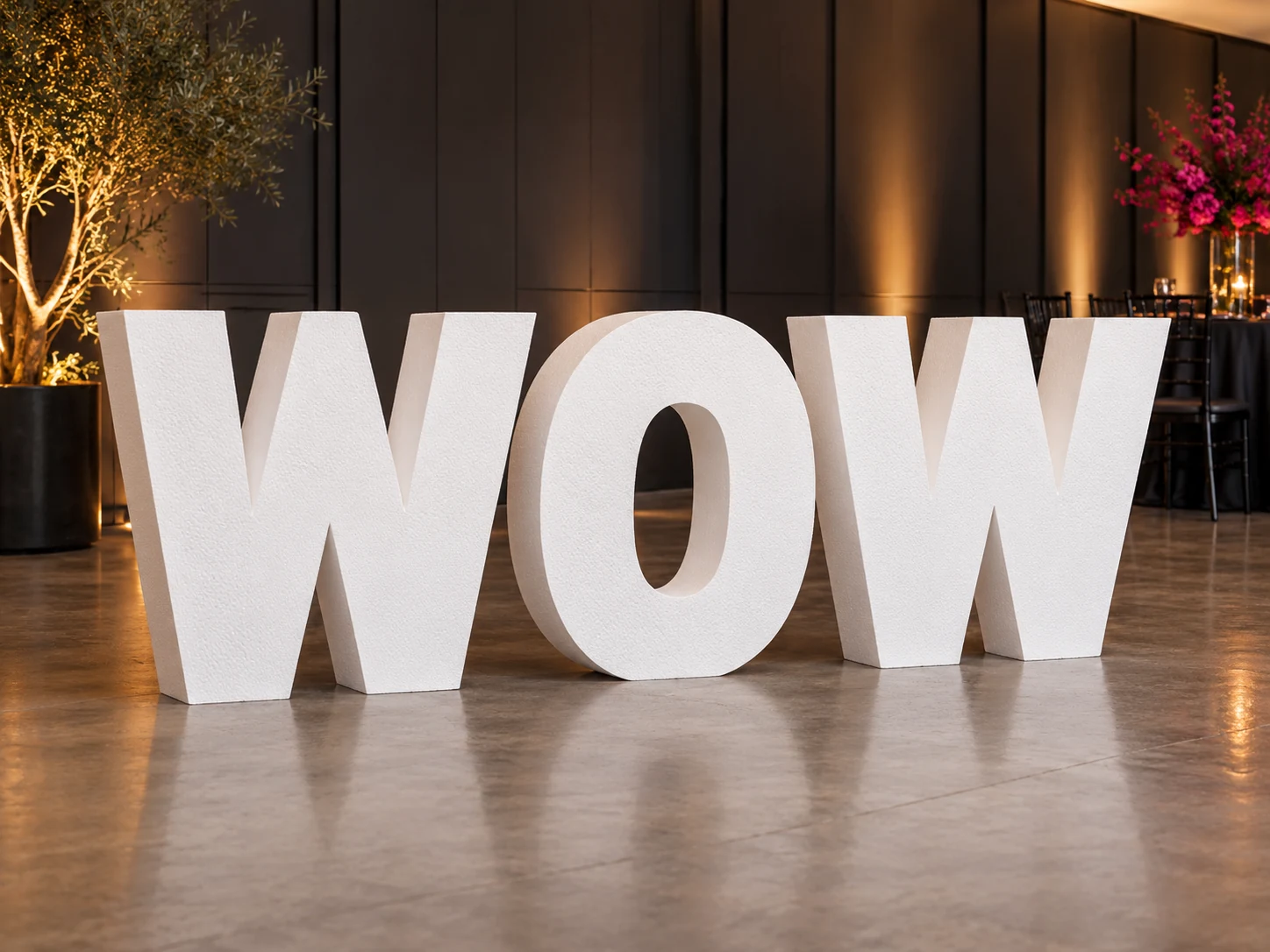 Illustrative giant white freestanding WOW foam letters displayed at an event venue